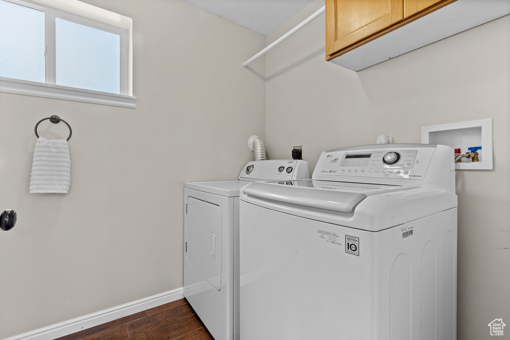 Laundry room featuring cabinet space, washing machine and clothes dryer, and dark wood finished floors