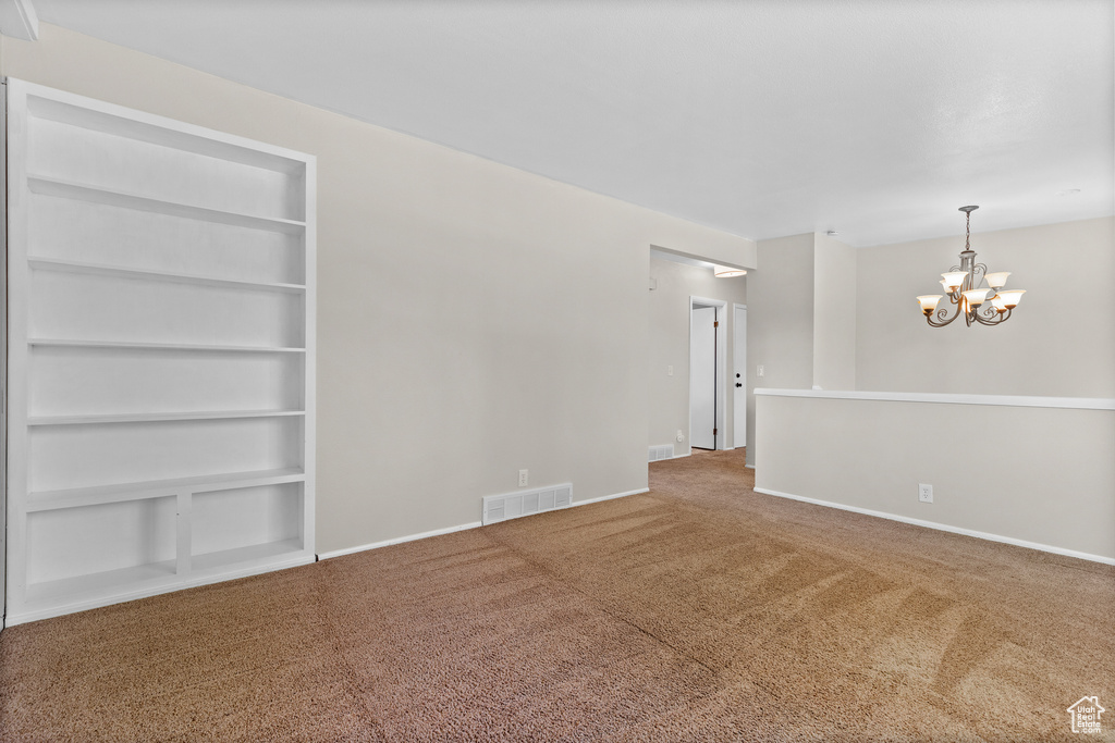 Spare room with carpet, a chandelier, and built in features