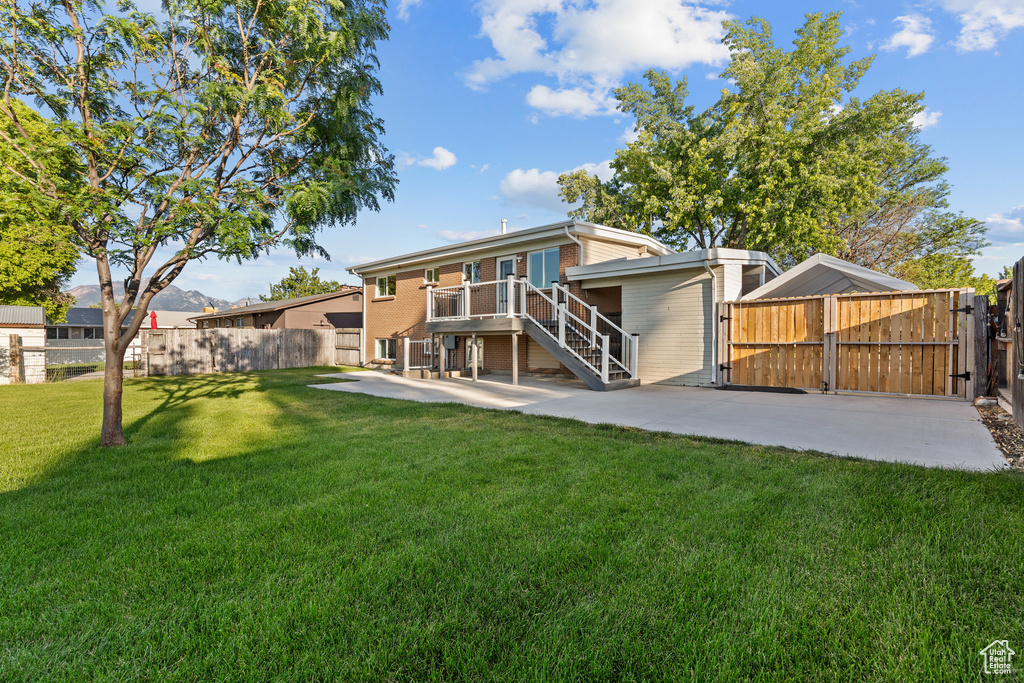 Rear view of property with a gate, a patio area, a fenced backyard, and stairs