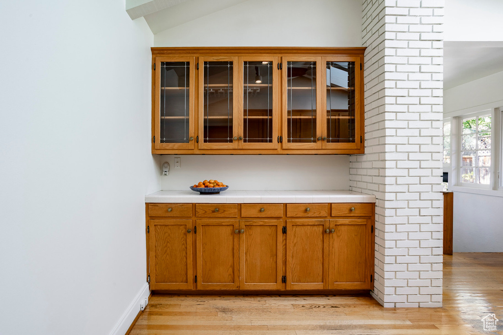 Bar area featuring light wood finished floors and vaulted ceiling