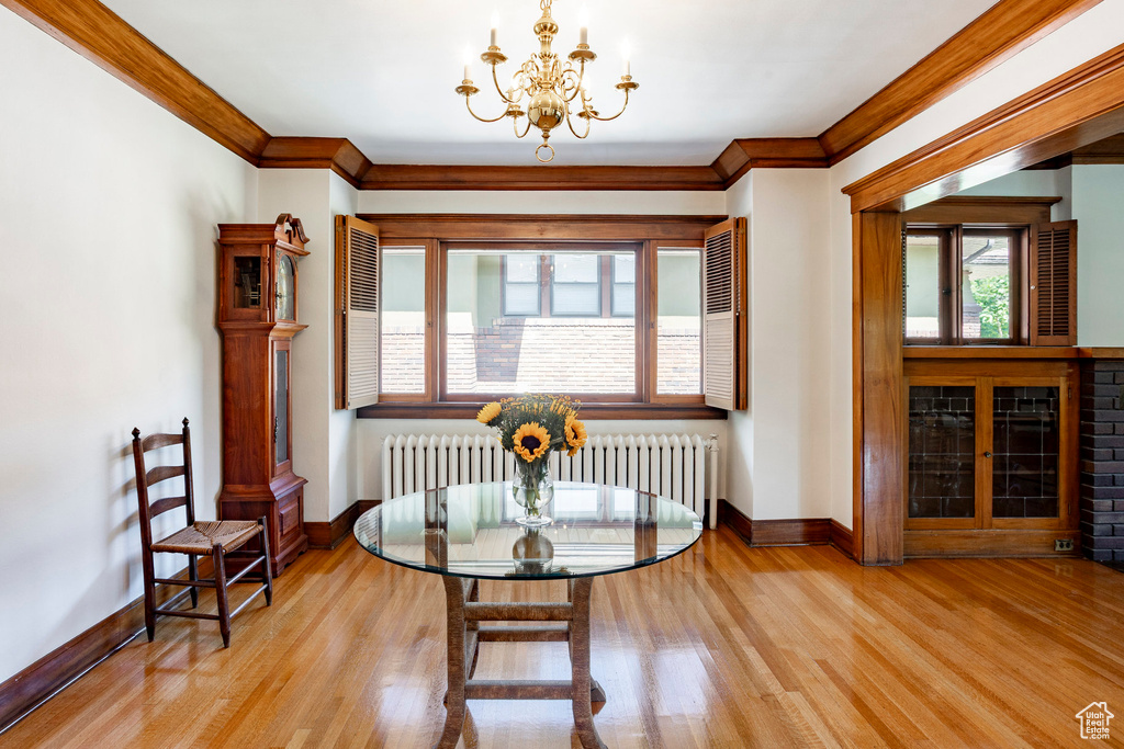 Dining area featuring radiator, a chandelier, wood finished floors, and ornamental molding