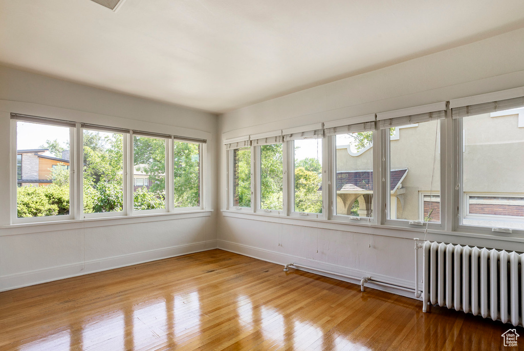 Unfurnished sunroom with radiator and wood-type flooring