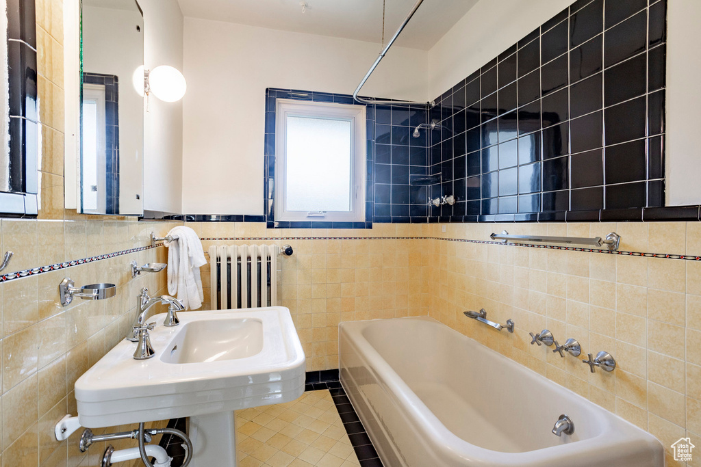 Bathroom with tile walls, radiator heating unit, tile patterned flooring, and shower / tub combination