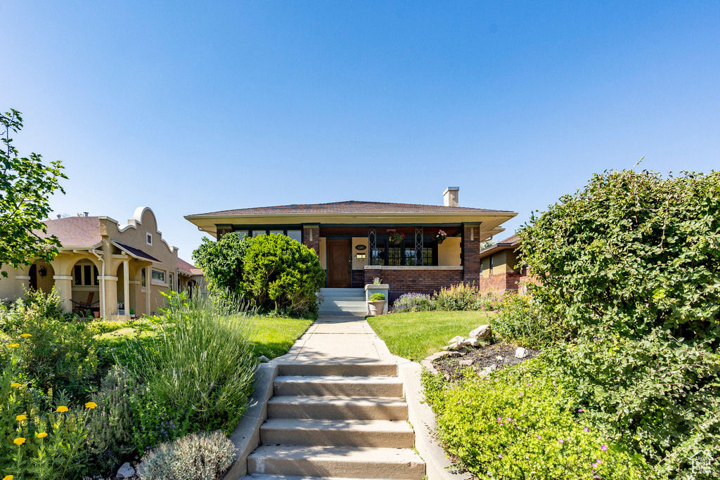 View of front of home with brick siding and a chimney
