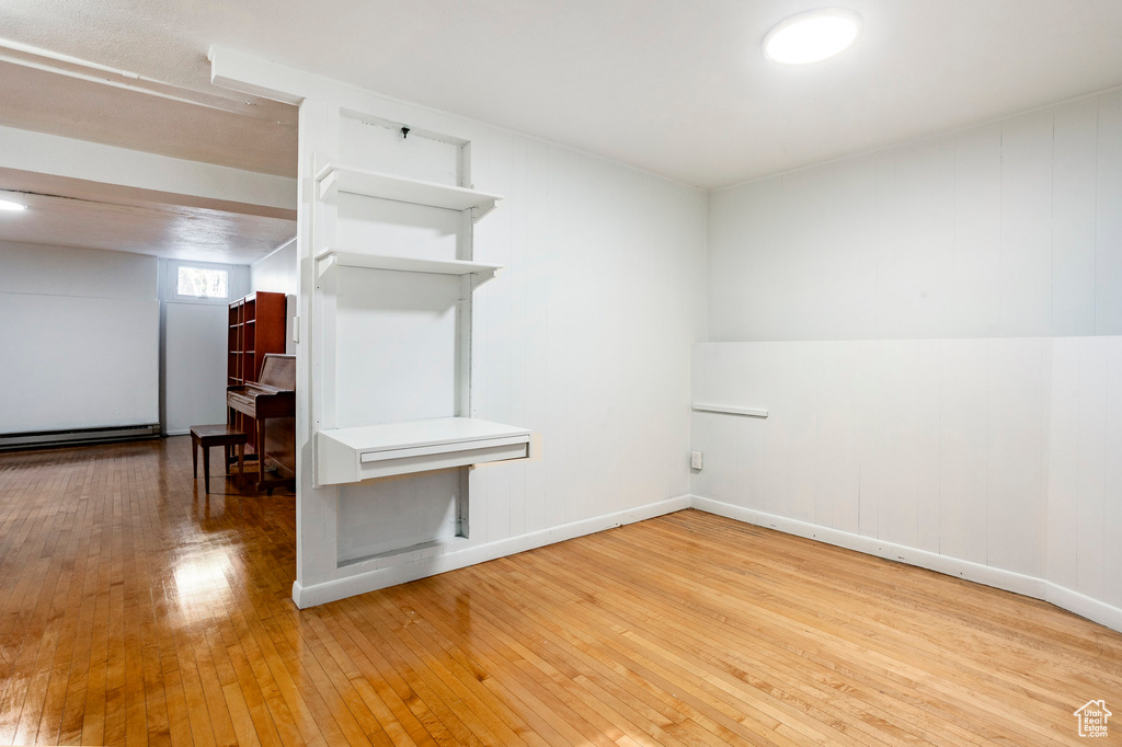 Spare room featuring wood-type flooring and a baseboard heating unit