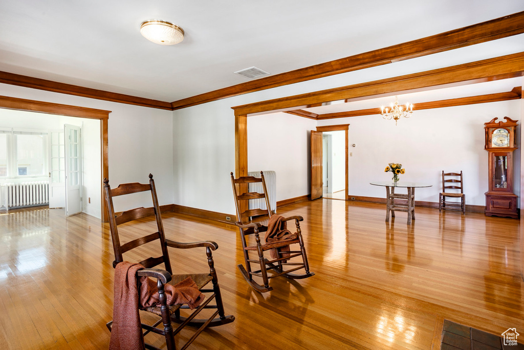 Dining area featuring radiator heating unit, wood finished floors, ornamental molding, and a chandelier