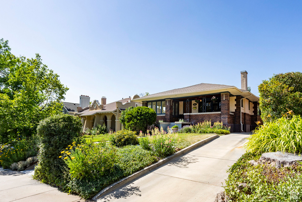 View of front of house featuring brick siding, concrete driveway, and a chimney