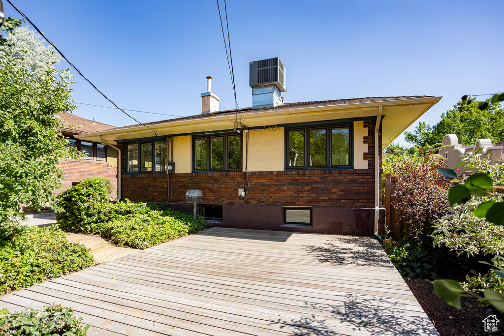 View of front of house featuring brick siding, a deck, and a chimney