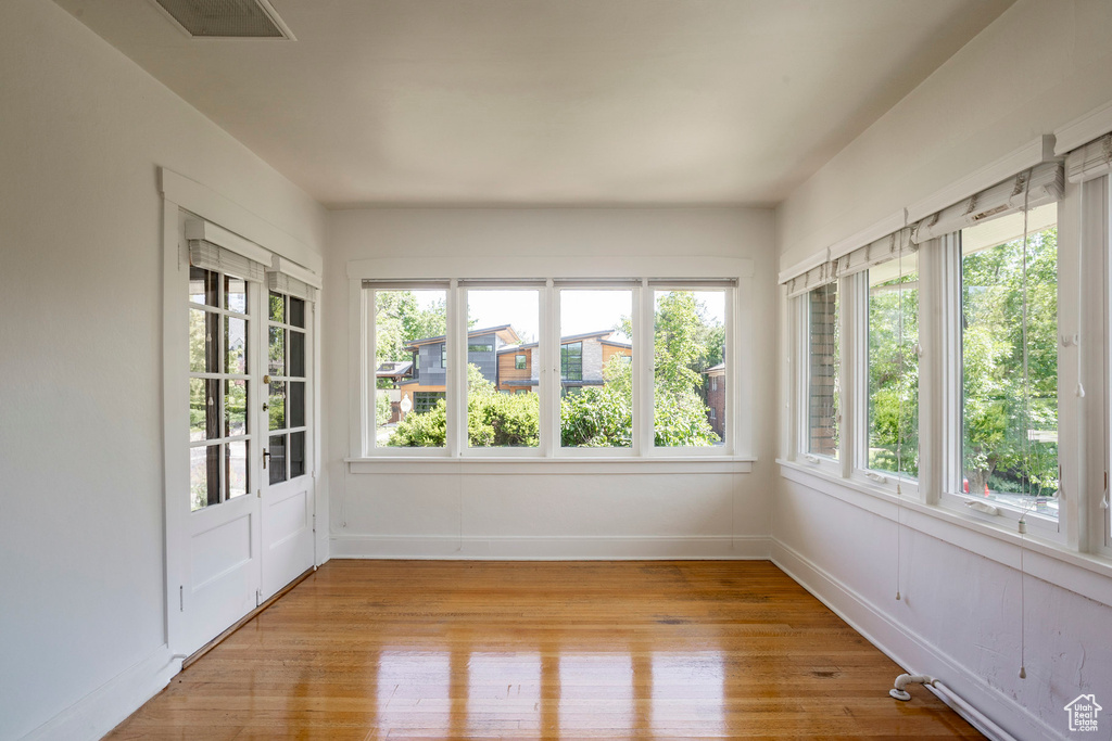 Unfurnished sunroom with wood finished floors and french doors