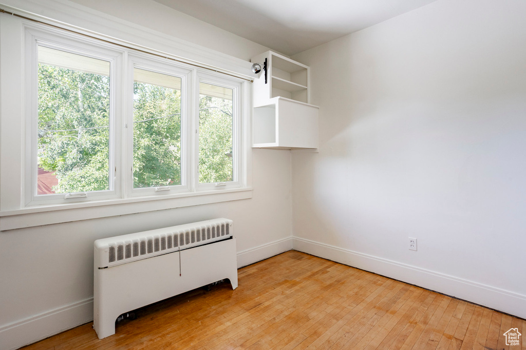 Unfurnished room featuring radiator, healthy amount of natural light, and light wood-type flooring
