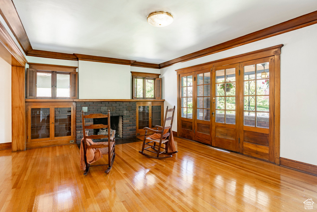 Sitting room featuring wood finished floors, ornamental molding, and a brick fireplace