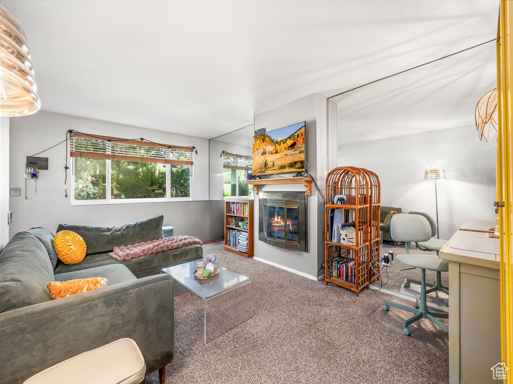 Carpeted living area featuring a glass covered fireplace and baseboards