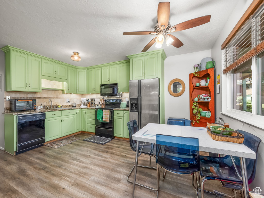 Kitchen featuring black appliances, a ceiling fan, tasteful backsplash, and wood finished floors