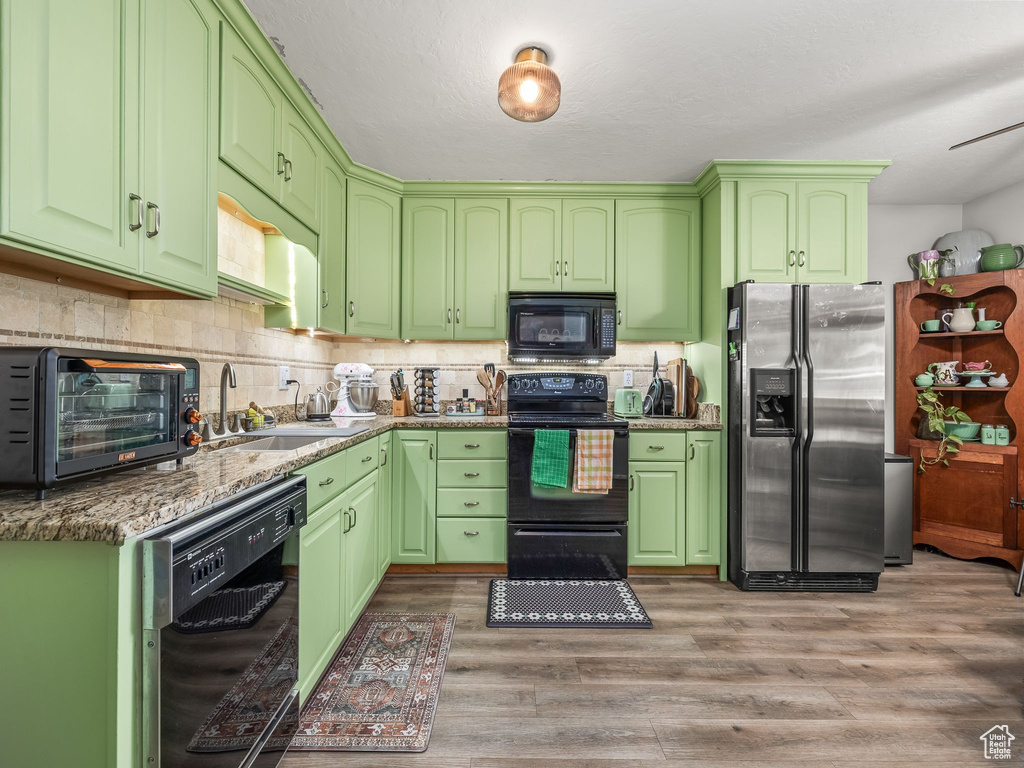 Kitchen with black appliances, light wood-style floors, and backsplash