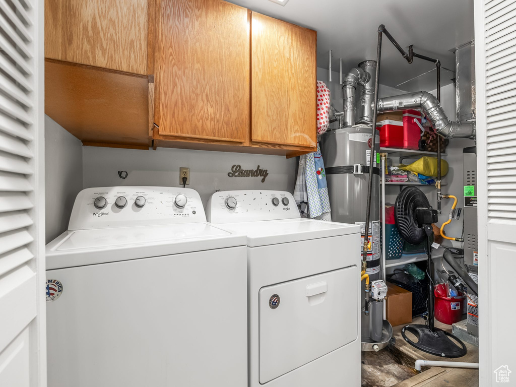 Laundry area featuring cabinet space, washing machine and clothes dryer, and secured water heater