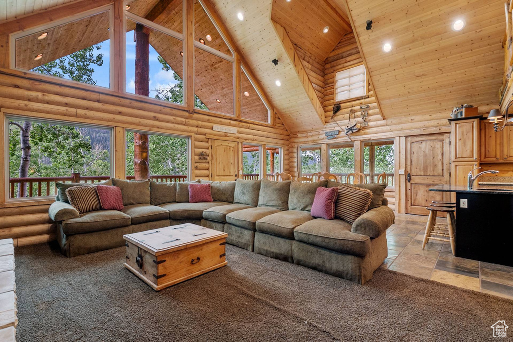 Living room featuring high vaulted ceiling, rustic walls, recessed lighting, wood ceiling, and plenty of natural light