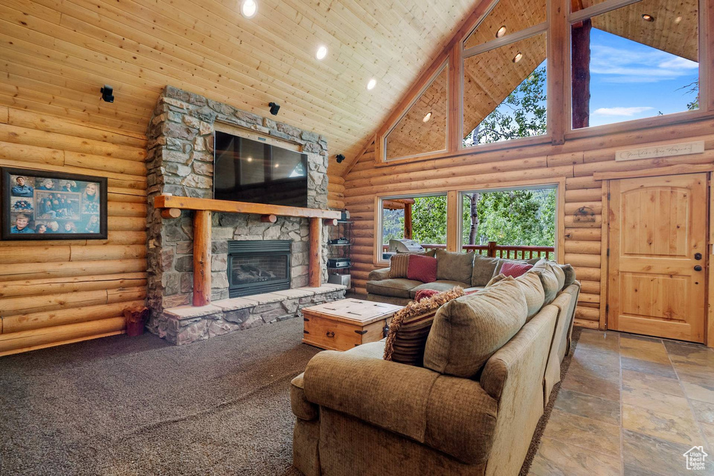 Living room with high vaulted ceiling, a stone fireplace, rustic walls, wood ceiling, and recessed lighting
