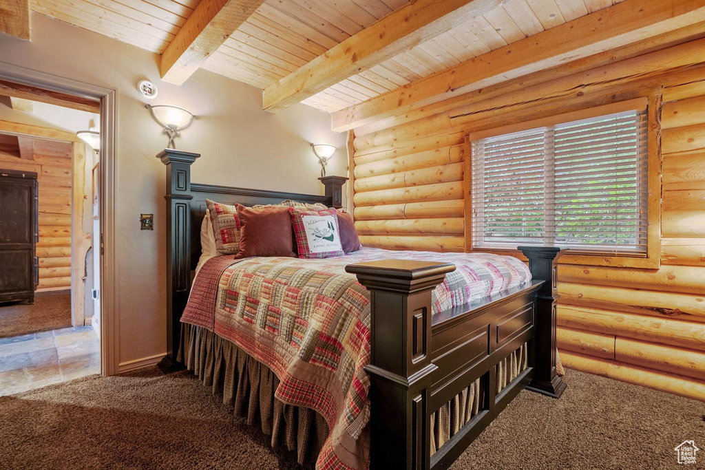 Bedroom with a wood ceiling with exposed beams, carpet flooring, and log walls