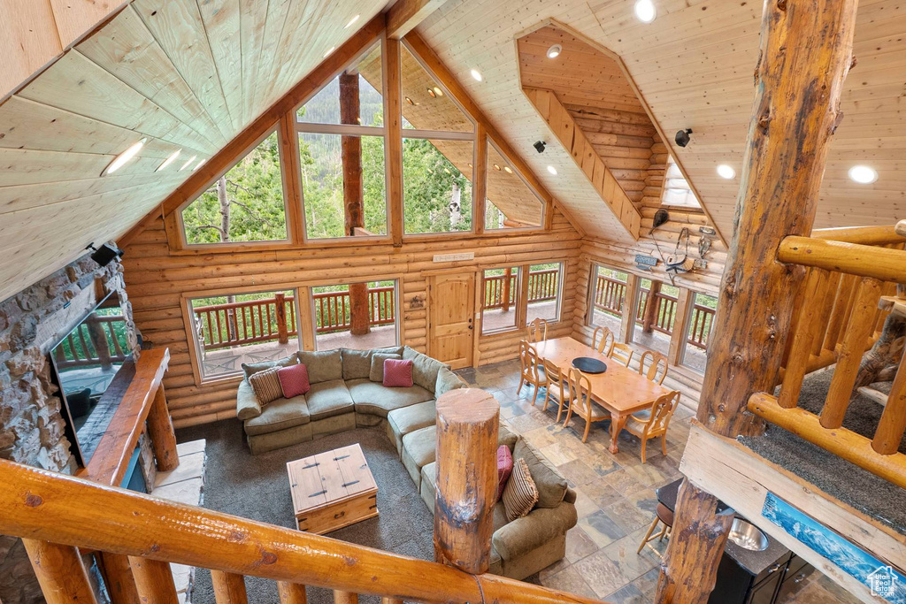 Living area featuring high vaulted ceiling, log walls, wooden ceiling, recessed lighting, and a stone fireplace