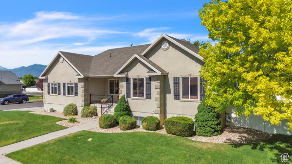 Single story home featuring a front lawn, stucco siding, and a mountain view
