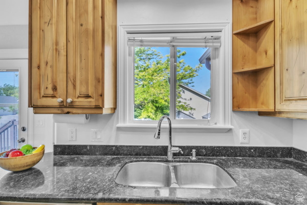 Kitchen featuring dark stone countertops, healthy amount of natural light, and brown cabinets