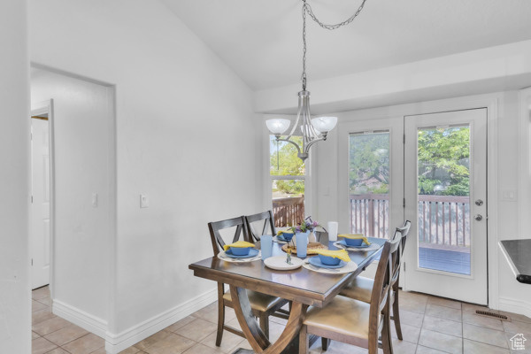 Dining space featuring lofted ceiling, a chandelier, and light tile patterned flooring