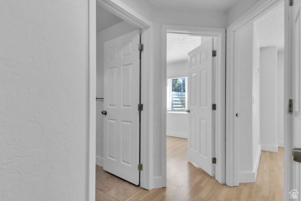 Corridor featuring light wood finished floors and a textured wall
