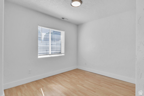 Unfurnished room featuring wood finished floors and a textured ceiling