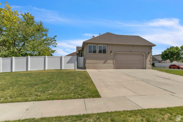 View of front of home featuring an attached garage, driveway, and stucco siding