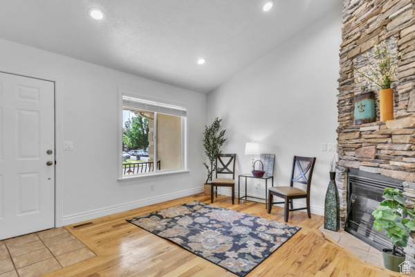 Foyer with wood finished floors, a stone fireplace, and recessed lighting