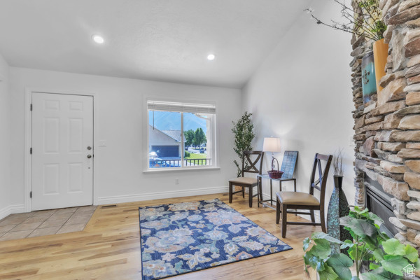 Entrance foyer with a fireplace, wood finished floors, vaulted ceiling, and recessed lighting