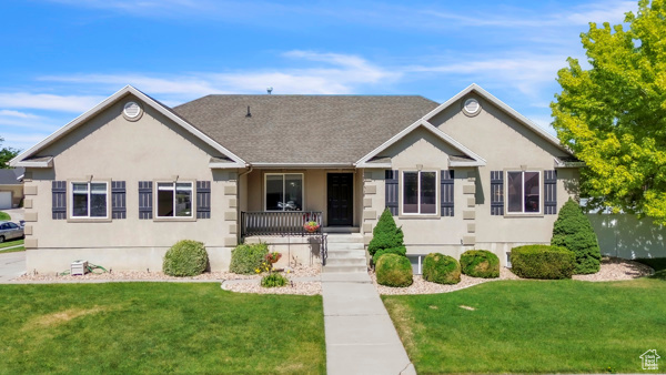 Ranch-style home with covered porch, a front yard, and stucco siding