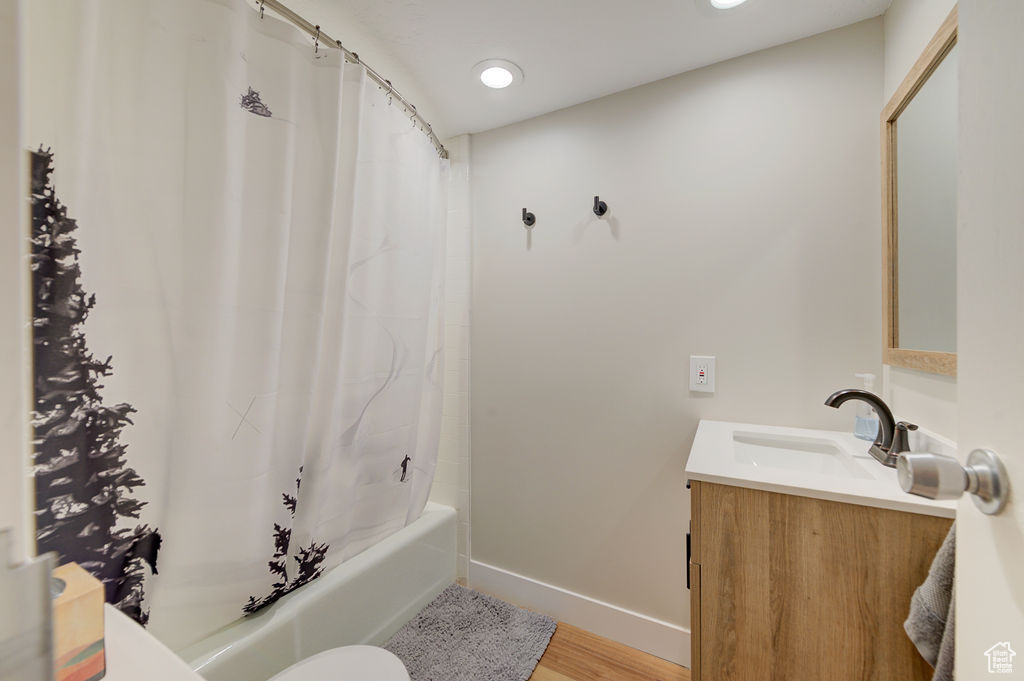 Full bath with vanity, shower / bath combo with shower curtain, wood finished floors, and recessed lighting