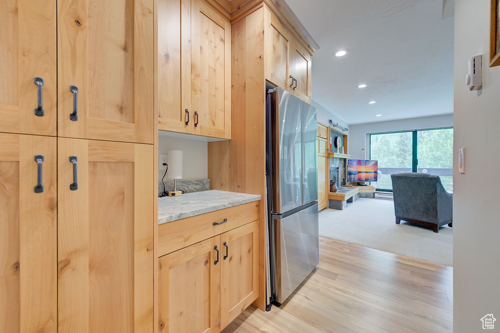 Kitchen with freestanding refrigerator, light brown cabinets, recessed lighting, light wood-type flooring, and open floor plan