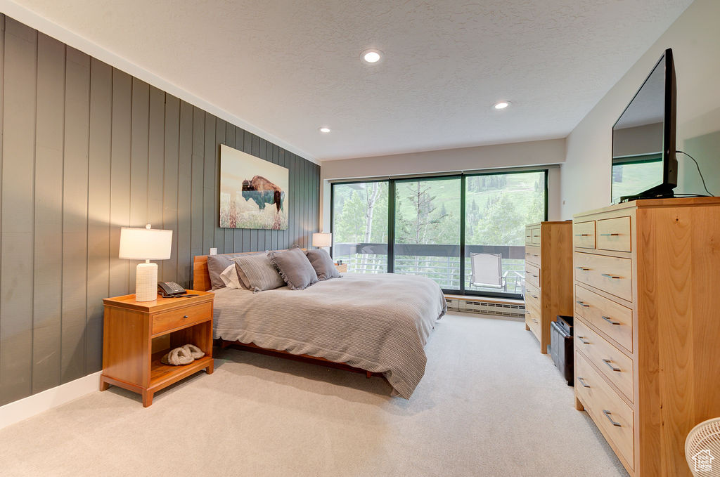 Bedroom featuring light carpet, a textured ceiling, recessed lighting, and baseboard heating