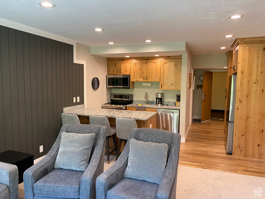 Kitchen featuring appliances with stainless steel finishes, open floor plan, light wood-style flooring, recessed lighting, and light brown cabinetry