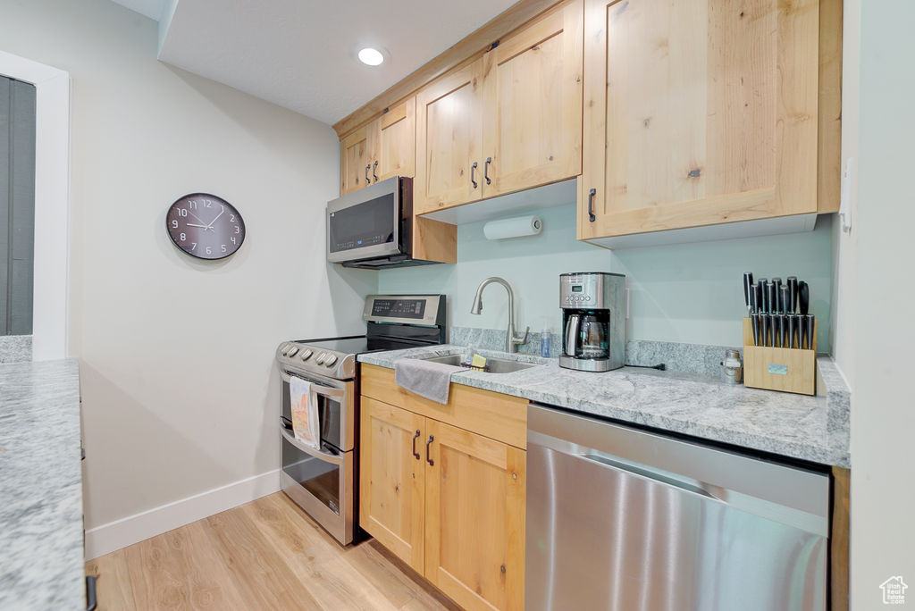 Kitchen with appliances with stainless steel finishes, light brown cabinets, light wood-style flooring, and recessed lighting