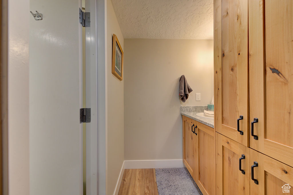 Bathroom featuring a textured ceiling, vanity, and wood finished floors