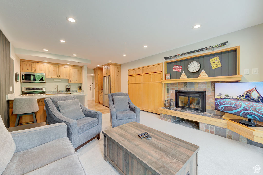 Living area with recessed lighting, light colored carpet, and a tiled fireplace