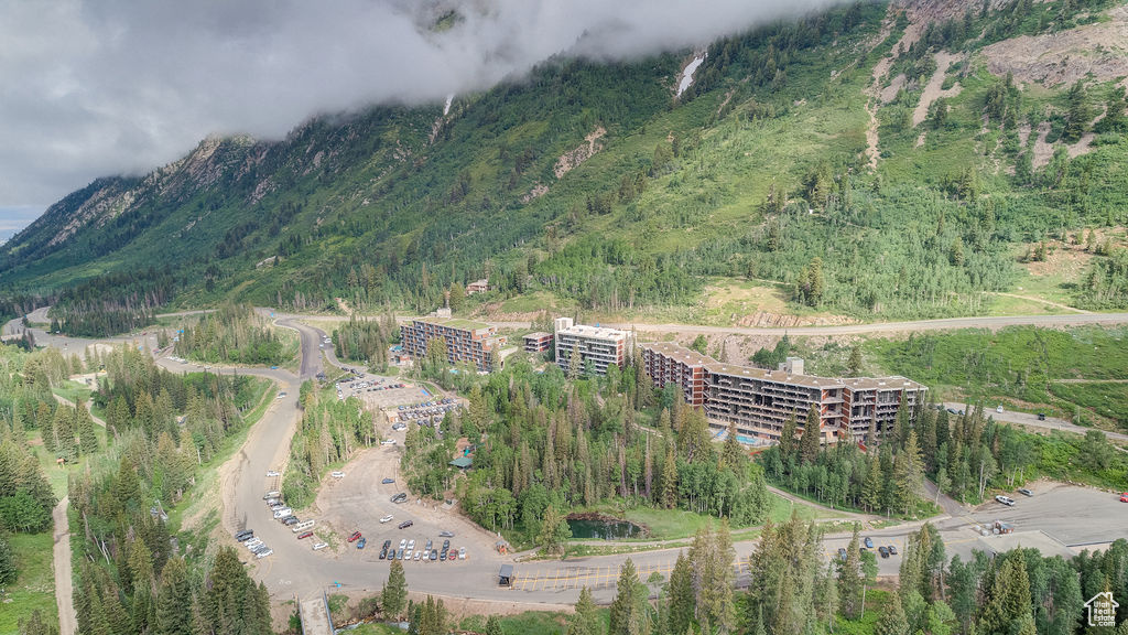 Aerial view of property and surrounding area with a mountainous background and a heavily wooded area