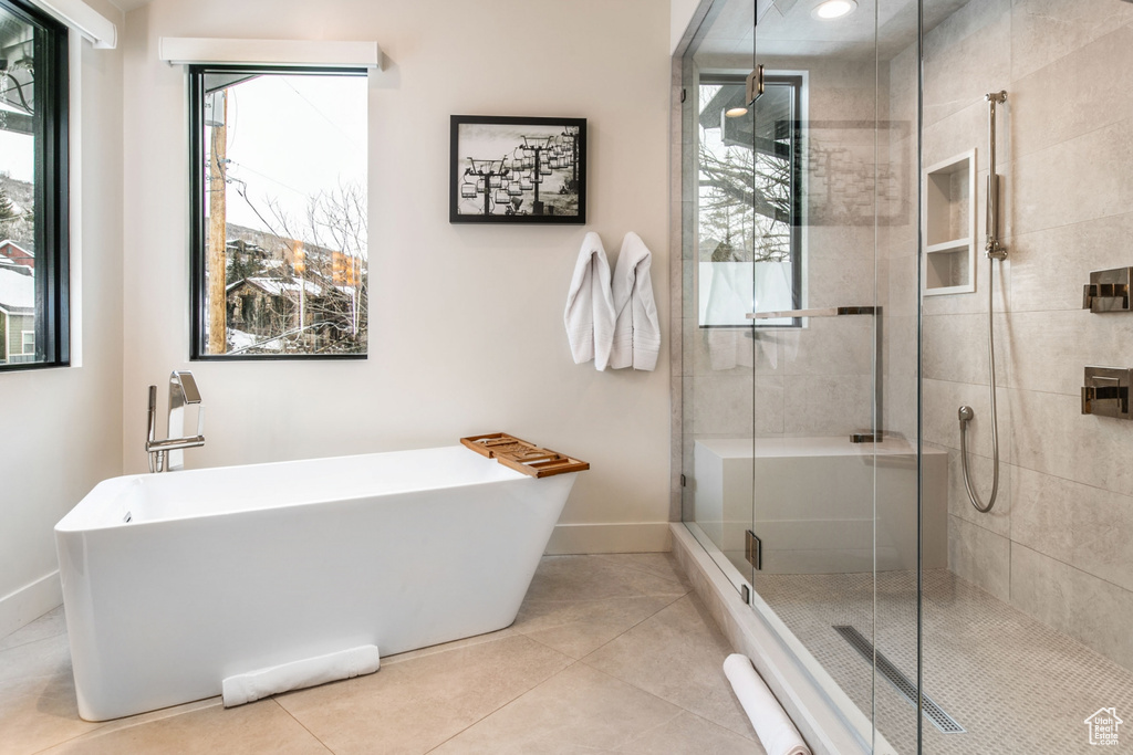 Bathroom with a freestanding tub, a shower stall, healthy amount of natural light, and tile patterned flooring