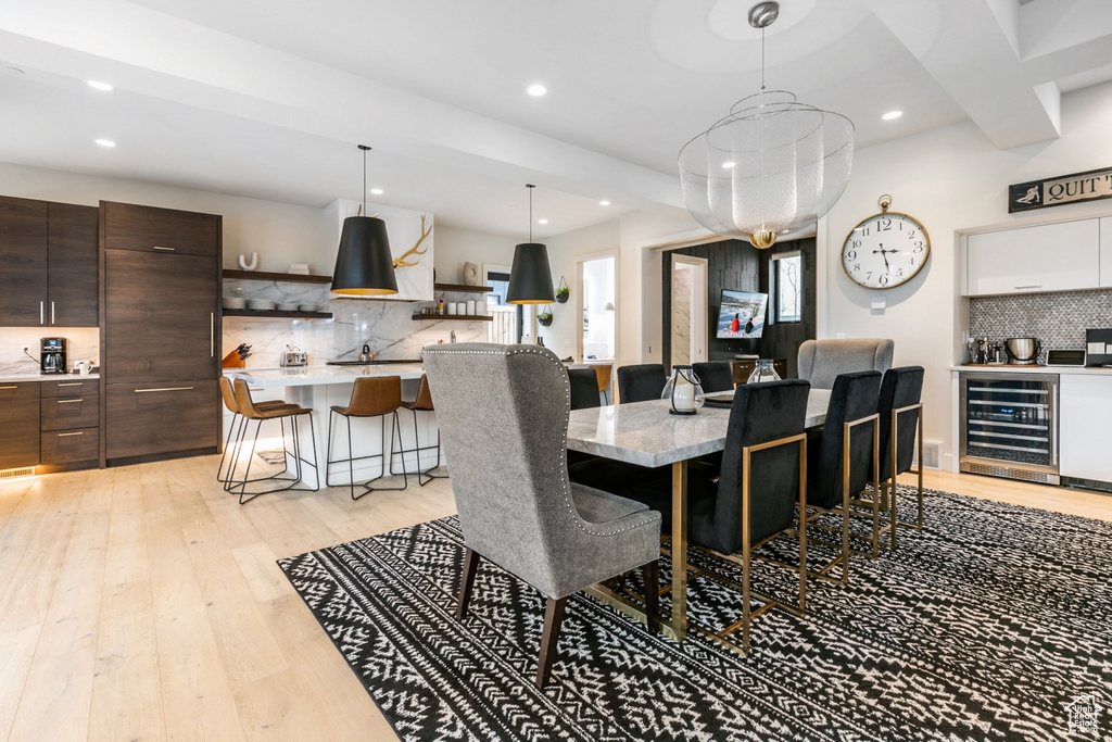 Dining space with wine cooler, recessed lighting, light wood-style floors, and bar