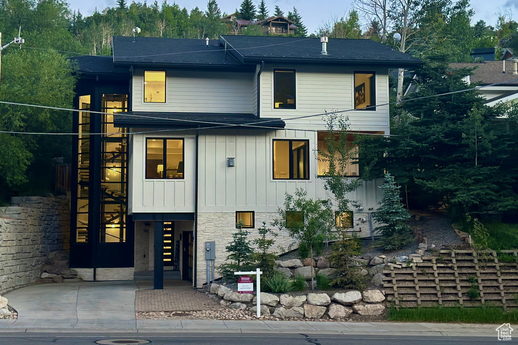 Contemporary home featuring board and batten siding, stone siding, and stairway