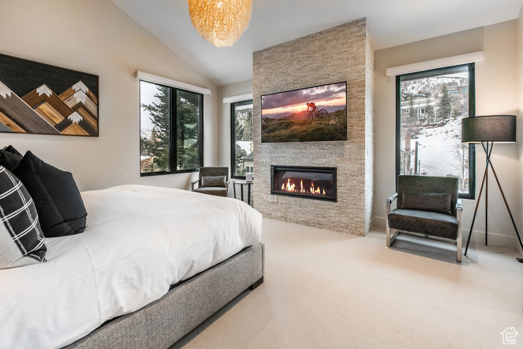 Bedroom with vaulted ceiling, carpet, and a stone fireplace
