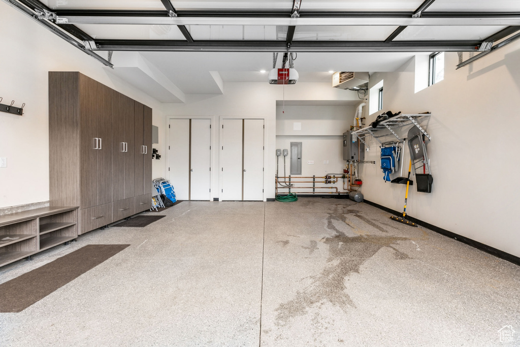 Garage featuring a garage door opener, electric panel, and a wall mounted AC