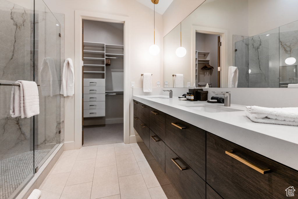 Bathroom with a spacious closet, a marble finish shower, double vanity, tile patterned flooring, and lofted ceiling