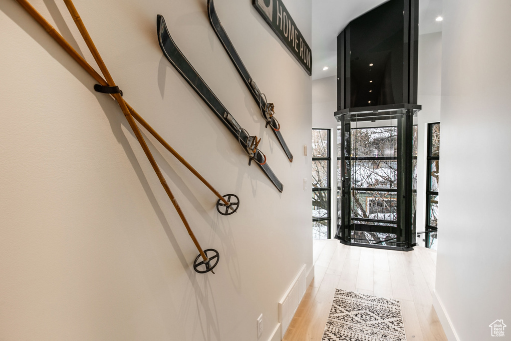 Hallway featuring light wood-type flooring and a towering ceiling