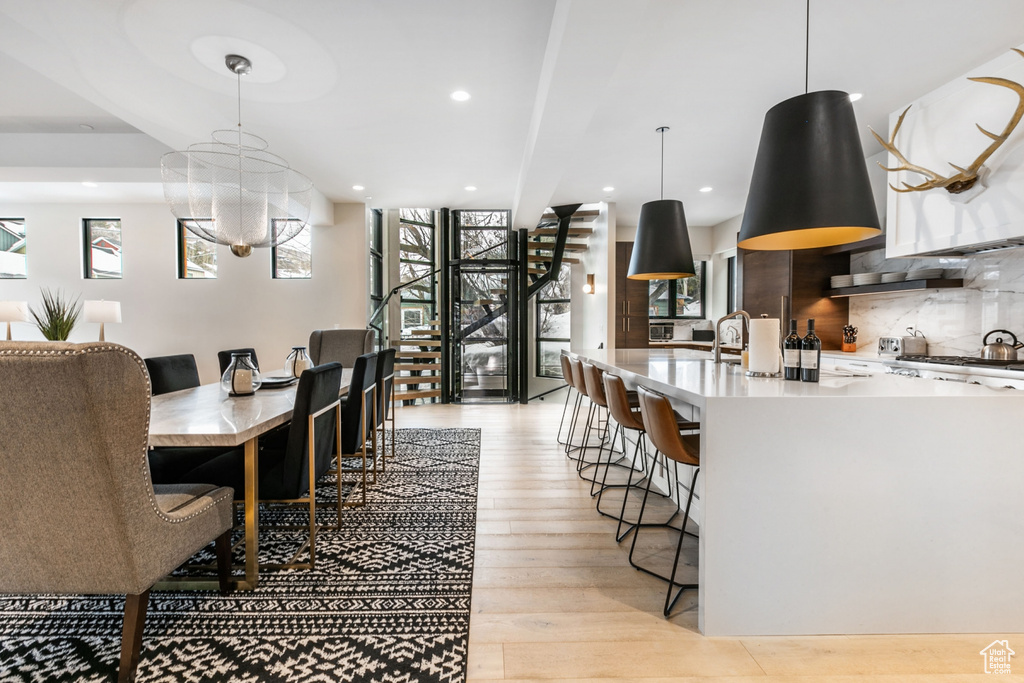 Dining space with stairs, healthy amount of natural light, light wood-style floors, recessed lighting, and a chandelier