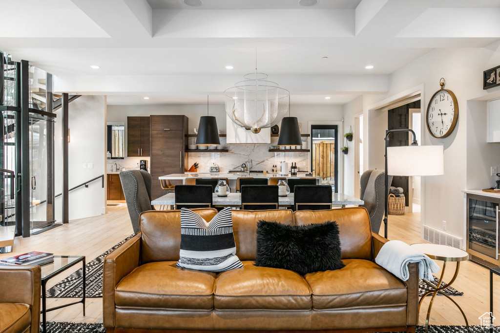 Living room with light wood finished floors, wine cooler, recessed lighting, and a chandelier