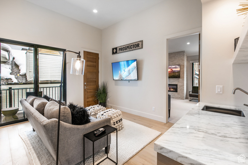 Living room featuring light wood-style flooring, a large fireplace, and recessed lighting